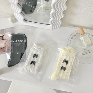 Gros plan détaillé de chaussettes JK avec nœuds et textures dentelle dans leur emballage