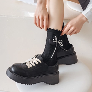 Detail of Lolita knee-high socks with double bows and ruffled edges on black platform shoes