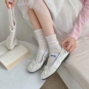 Detail of white ballet flats with bow and ribbed frill socks in a soft lifestyle setting