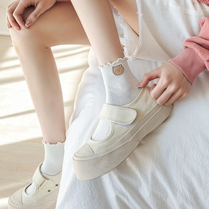 Détail de chaussettes à volants blanches brodées d'ours avec chaussures Mary Jane à plateau