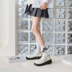 Detail of white ruffle socks with black bows paired with platform Mary Jane shoes