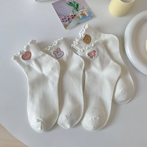 Détail de chaussettes blanches à volants avec broderies de lapin et ours mignons