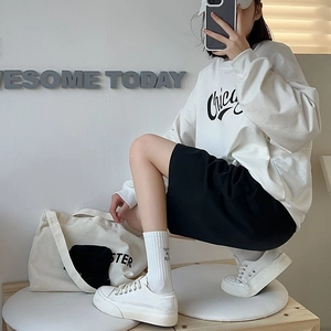Detail of white mid-calf socks with letter embroidery worn with white canvas sneakers