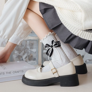 Detail of white lolita lace socks with double bows and ruffled edges worn with mary janes