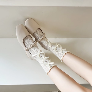 Detail weißer hohl geschnittener Spitzensocken mit Satinschleifen und Mary Jane Schuhen