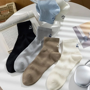 Close-up of crew socks in five colors featuring stylish letter embroidery and breathable texture