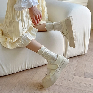 Detail of cream platform Mary Janes with white cable-knit jacquard mid-calf socks