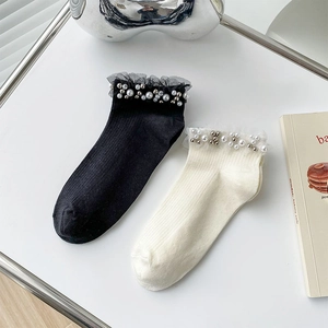 Close-up of ribbed cotton socks featuring elegant lace trim and faux pearl embellishments