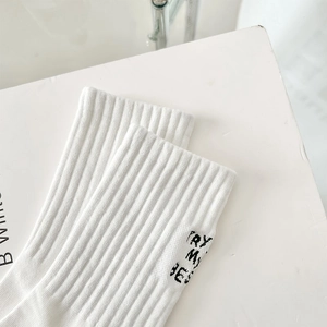Detail of white ribbed crew sock featuring black TRY MY BEST embroidery on the side