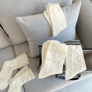 Close-up of white JK socks with lace edges, cable knit textures and floral patterns