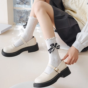 Detail of white Lolita socks with double black bows and Mary Jane shoes close-up