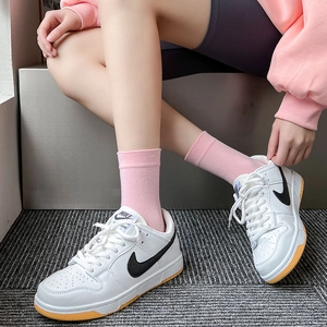 Close-up of white leather low-top sneakers with black logo and pink knitted crew socks