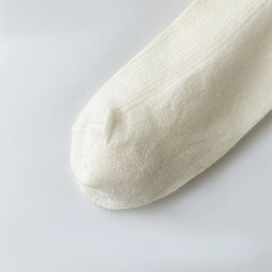 Macro detail of white cotton knit socks showing fine ribbed texture and seamless toe stitching