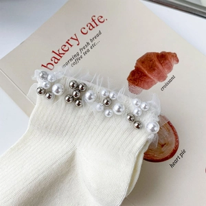Detail of white mesh lace trim with pearls and silver beads on cream cotton ankle socks