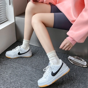 Close-up of white leather low-top sneakers with black logo and cotton socks on a model