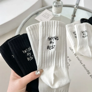 Detail of ribbed knit cotton socks with TRYING MY BEST embroidery in black and white