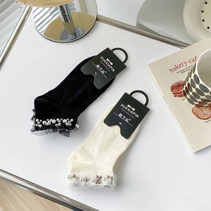 Close-up of lace trim and pearl beads on white and black cotton ankle socks