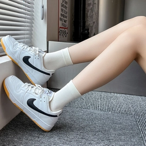 Detail of white leather low-top sneakers with black swoosh and yellow rubber sole