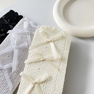 Detailansicht von durchbrochenen Spitzensocken mit eleganten Schleifen in Weiß, Beige, Schwarz
