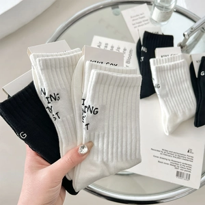 Detail of ribbed cotton mid-calf socks with letter embroidery and paper packaging