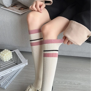 Detail shot of cream-colored knee socks with pink stripes showing elastic knit fabric