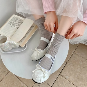Detail of white ruffle socks with ballet flats and ribbons in a soft aesthetic style