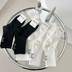 Detail of knit crew socks with TRY MY BEST embroidery and ribbed cuffs on glass table