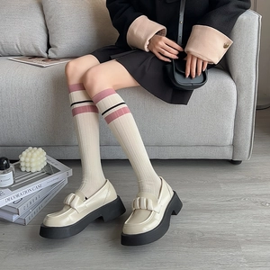 Detail of cream loafers with chunky black soles and pink striped ribbed calf socks