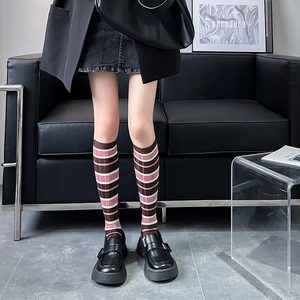 Detail view of pink and brown striped knee-high socks styled with platform loafers