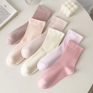 Detail of five pairs of Morandi colored mid-calf socks with ribbed texture on white table