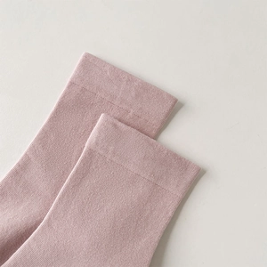 Detailed macro view of the dusty pink ribbed knit fabric on cotton mid-calf socks