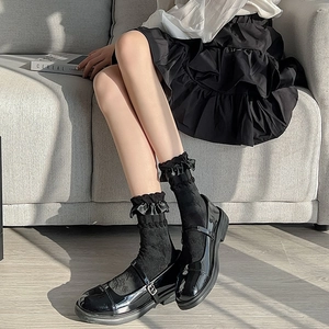Close-up of black frilly ruffle socks paired with glossy patent Mary Jane shoes