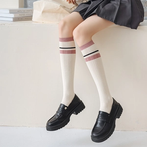 Detailed view of white calf socks with pink stripes paired with black platform loafers