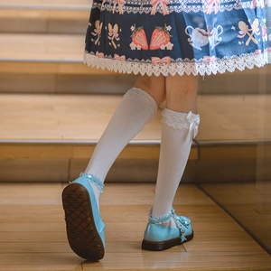 Détail de chaussettes Lolita blanches avec dentelle et nœuds sur chaussures bleues