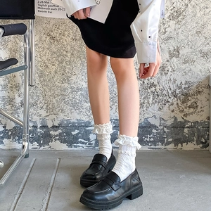 Close-up of white ruffle frill socks paired with black platform loafers for a vintage look