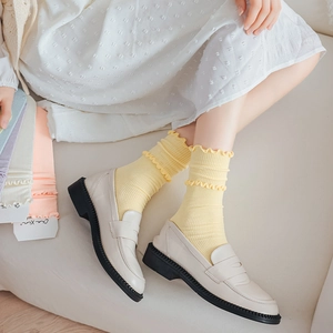 Detail of ruffled cuff ankle socks in vibrant yellow paired with beige leather loafers