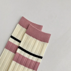 Macro shot of ribbed knit knee high socks featuring vintage pink and black stripe details