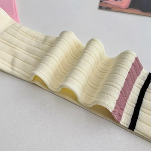 Detailed close-up of ribbed knit cream socks with pink and black striped cuffs