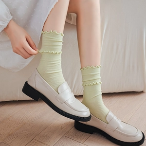 Light green ruffled socks with vertical stripes paired with beige platform loafers
