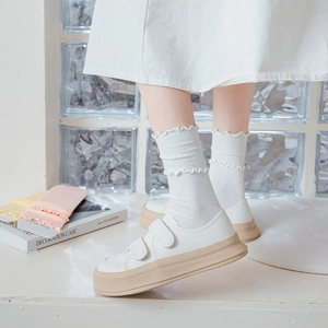 Detail of white ruffle socks paired with cream platform sneakers and velcro straps