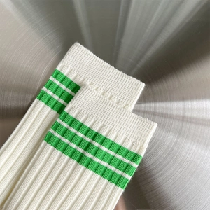 Details von gerippten elfenbeinfarbenen Socken mit grünen Streifen auf Metall