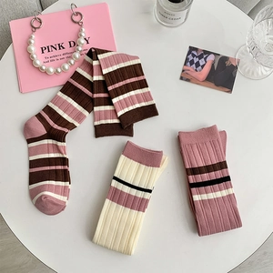 Flat lay of pink striped knee-high socks set with cozy ins-style lifestyle props