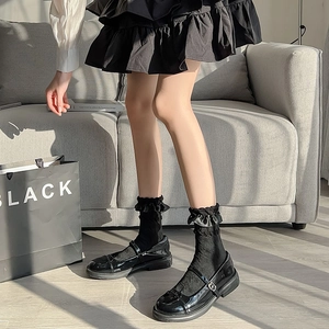 Detail of black Mary Jane shoes paired with ruffled socks in natural window light