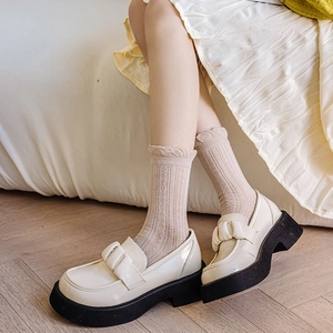 Detail of cream platform loafers with bow decoration and beige lace mesh socks