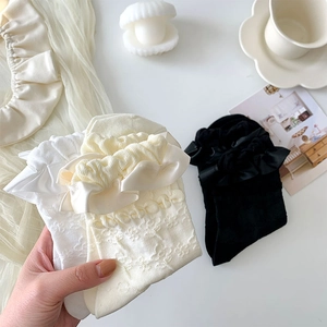 Detailed shot of Lolita style white socks featuring large lace ruffles and silk ribbon bows