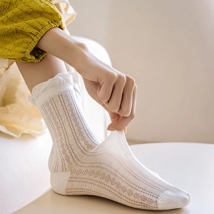 Detail of white mesh socks showing the breathable hollow lace pattern and elastic frilly cuff