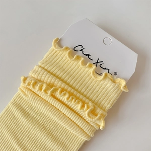 Detail of light yellow ribbed knit socks featuring delicate ruffled lettuce edges