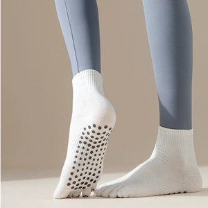 Detail view of white five-toe yoga socks with black anti-slip silicone dots on the sole