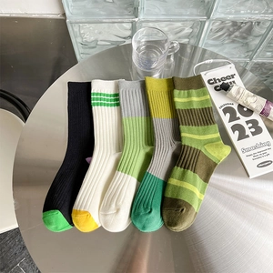 Set mit fünf gerippten Baumwollsocken in Grün- und Gelbtönen auf einem Metalltisch