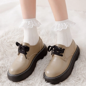 Gros plan de chaussures richelieu beiges à semelles compensées sur tapis blanc